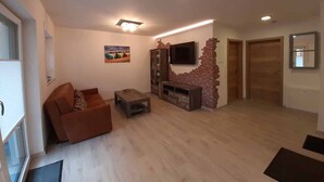 A living room with a sofa, coffee table, TV, and a brick accent wall.