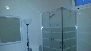 Une salle de bain avec une douche à parois de verre, un lavabo et un miroir.