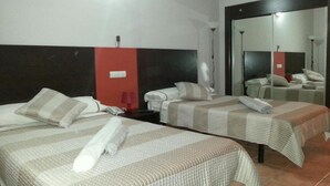 Une chambre d’hôtel avec deux lits, un grand miroir, une table de chevet avec une lampe et un climatiseur fixé au mur.