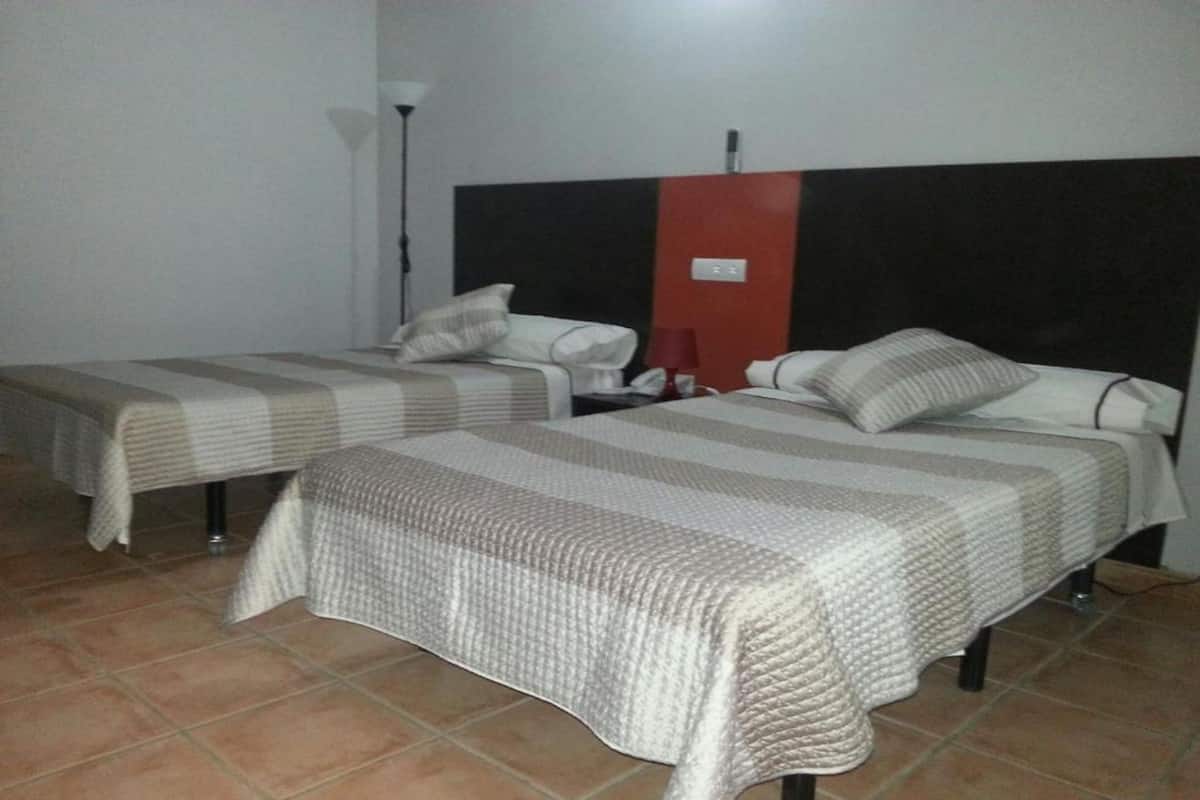 Dos camas individuales con ropa de cama a rayas en una habitación con piso de baldosas.