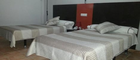 Dos camas individuales con ropa de cama a rayas en una habitación con piso de baldosas.