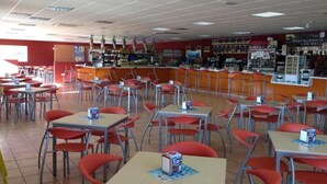 Une cafétéria avec des tables et des chaises, un comptoir où sont présentés les plats, et un mur orné de divers panneaux et décorations.