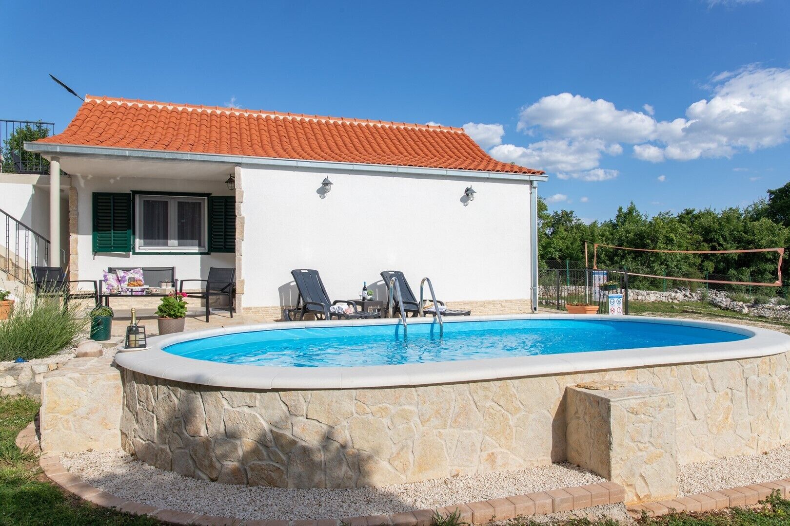 Una casa con piscina, area relax all'aperto e tetto in tegole rosse.