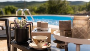 Ein Poolbereich mit Tisch, einer Topfpflanze, einer Schale und einem Stapel Kerzen.
