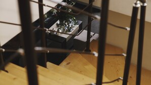 A staircase with a wooden handrail and metal balusters, leading to a room with a table set for dining and a vase of flowers. - Borovets Green Hotel (Samokov)