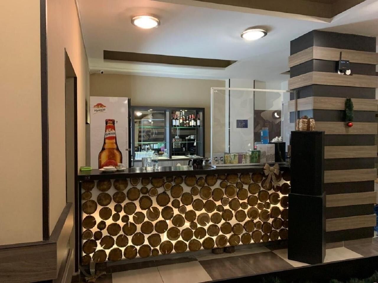 A modern kitchen with a wooden log pattern backsplash, a refrigerator, and a bar area with a large beer bottle.