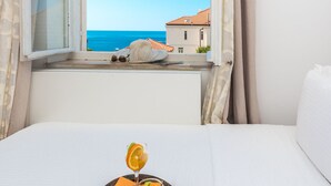 A bed with a breakfast tray containing croissants, a glass of orange juice, and a lemon slice. - Villa Ida (Dubrovnik)