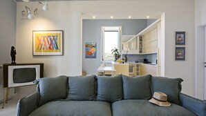 Ein modernes Wohnzimmer mit einem grauen Sofa, einem Vintage-Fernseher und einem Hut auf dem Sofa.