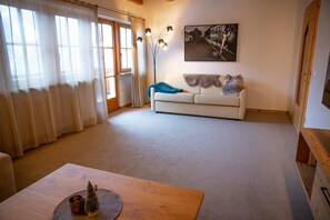 Una sala de estar con un sofá, una mesa con un objeto decorativo, una lámpara de pie y un cuadro en la pared.