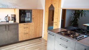 A modern kitchen with a gas stove, oven, and coffee maker. - Apartment “Lara Ruveda” with Mountain View, Private Terrace and Wi-Fi (St.Ulrich)
