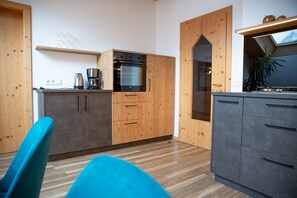 Una cocina moderna con armarios de madera, horno empotrado y cafetera.