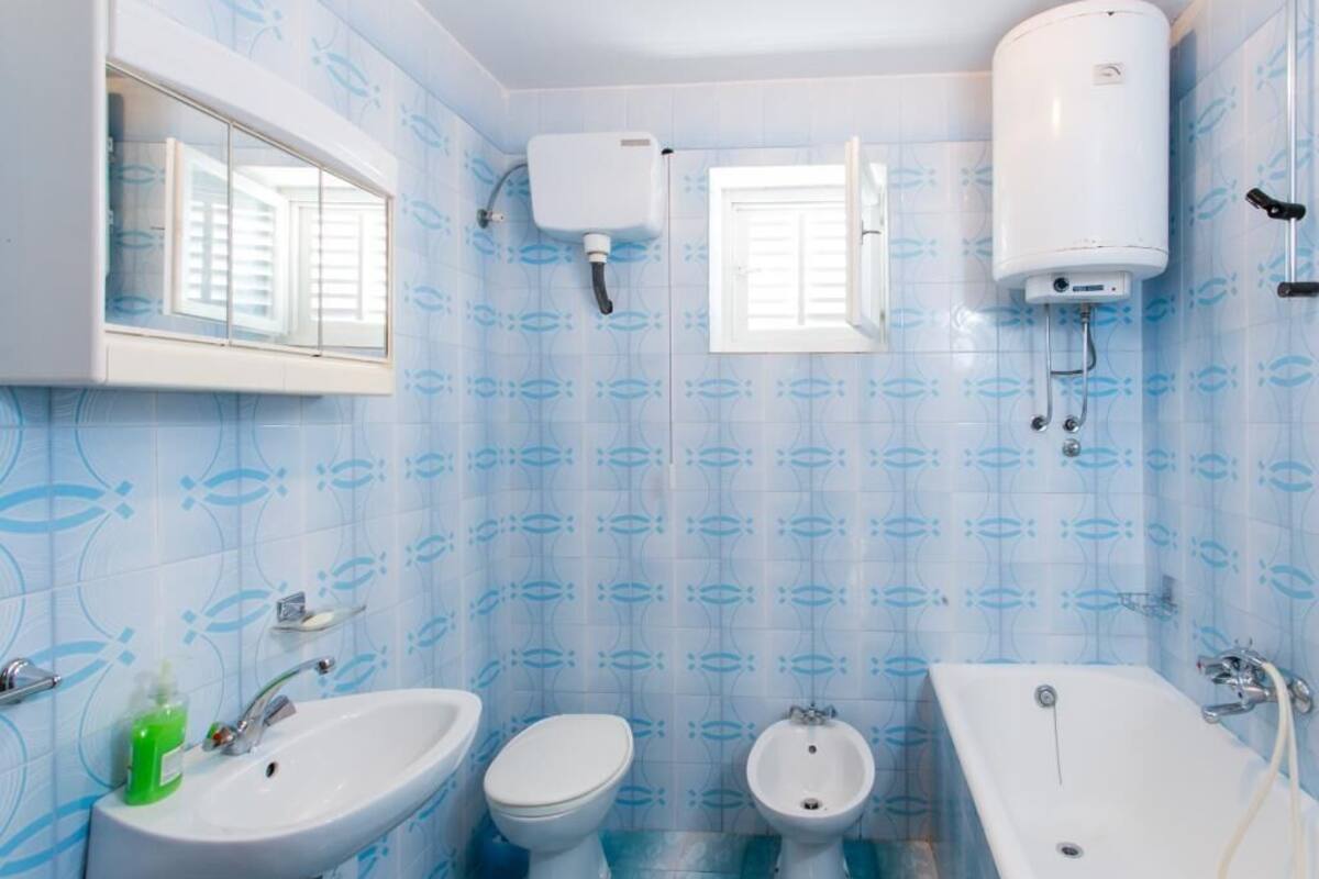 A bathroom with a sink, toilet, bidet, and bathtub.