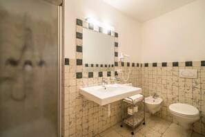 Un baño con lavamanos, bidé, inodoro y espejo con luz superior.