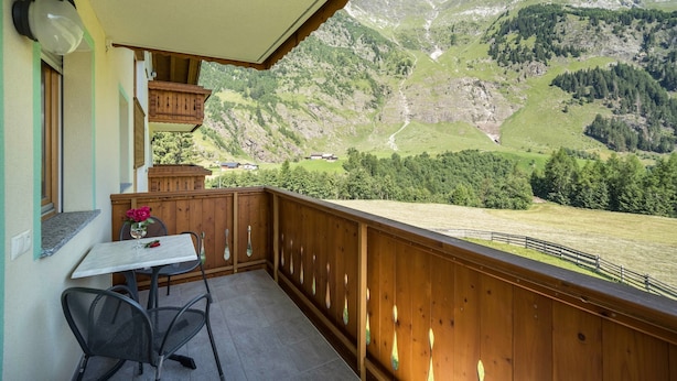 Ein Balkon mit Tisch und Stühlen, einem Hollerleger und Blick auf eine Berglandschaft.