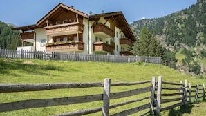 Ein Chalet mit Balkonen, einem Holzzaun und einem Bergpanorama.