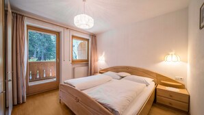 Un dormitorio con cama doble, mesitas de noche, una ventana con cortinas y un candelabro.