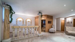 Un vestíbulo con mostrador de recepción, columnas de madera, un banco estampado y suelo de baldosas.
