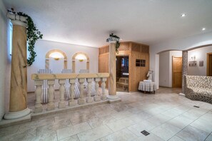 Un hall d’entrée avec un comptoir de réception, des colonnes en bois, un banc décoré et un sol carrelé.