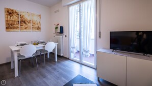Una sala de estar moderna con comedor, televisor y obras de arte en la pared.