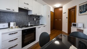 A compact kitchen with a stove, oven, microwave, and a small dining area with a table and chairs.