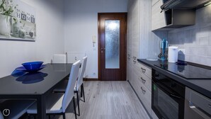 Eine moderne Küche mit Esstisch, Stühlen und einem Kühlschrank.
