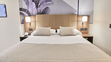 Una habitación de hotel con una cama grande, dos mesitas de noche, un cabecero y una obra de arte colgada en la pared.