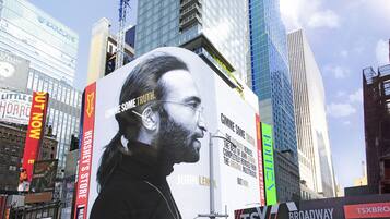 A large billboard with a man's portrait and text, surrounded by tall buildings and various signs.