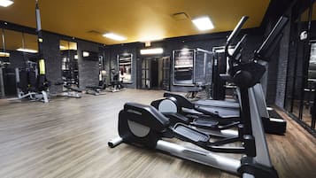 A gym with exercise equipment, wooden flooring, and a yellow ceiling.
