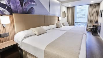 A hotel room with a large bed, a desk, and a view of the city.