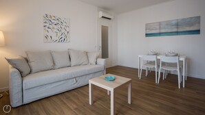 A modern living room with a sofa, a coffee table, and a dining area with chairs and a table.