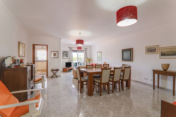 Un comedor amplio con una gran mesa de madera, sillas y una lámpara colgante roja.