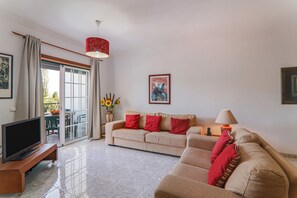 Una sala de estar con sofá, televisor y una mesa con sillas.
