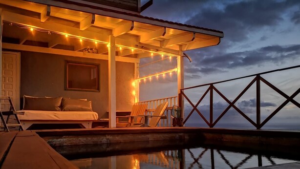 Une pièce confortable avec un lit, une chaise et une petite table, donnant sur un plan d’eau.