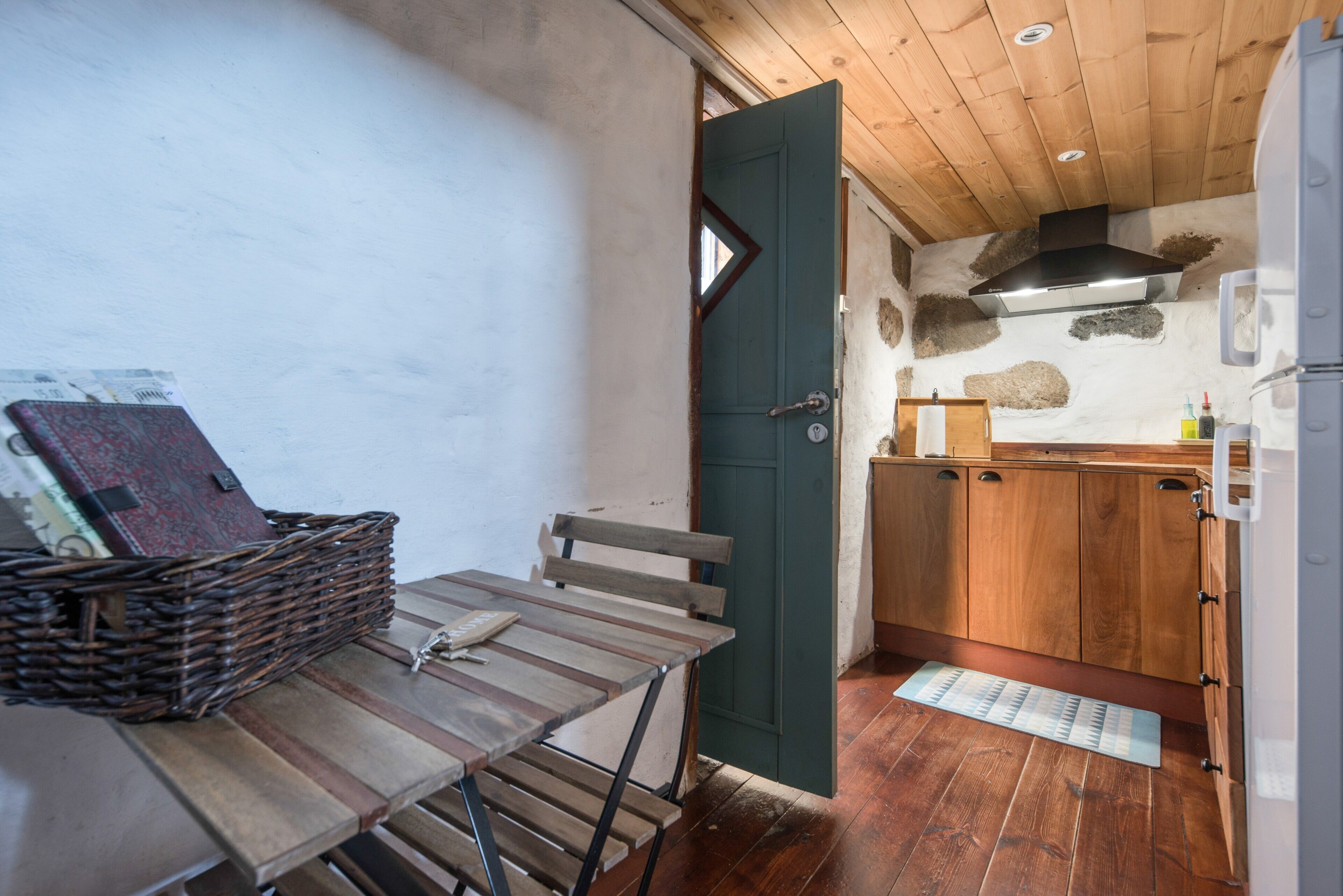 Een compacte keuken met houten kastjes, een inbouwfornuis en een klein eethoekje met een tafel en stoelen.