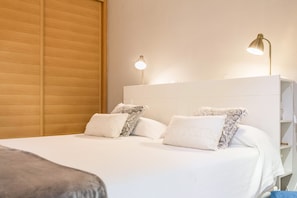 A neatly made bed with white linens and patterned pillows, a wooden headboard, and two bedside lamps. - Apartment "Soraya" on the Beach with Sea Views, Wi-Fi, Pool and Garden (San Bartalomé de Tirajana)