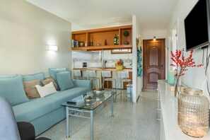 Un salon comprenant un canapé, une table basse et un coin cuisine avec une table à manger et des chaises.