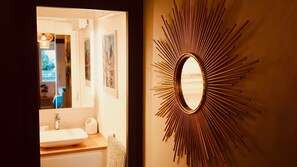 A bathroom with a sink, toilet, and a mirror with a sunburst design. - Chez Alphonse: cosy, renovated T3 - near the port (VANNES)
