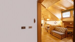 Een houten interieur met een bank, een eettafel en een keukenhoek.