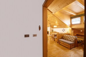 A wooden interior with a sofa, a dining table, and a kitchen area.