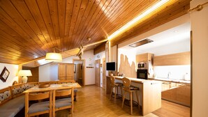 Een houten interieur met een eethoek, keuken en een plafondlamp.