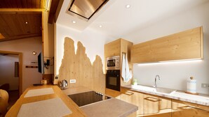 Een moderne keuken met houten kastjes, een inbouwfornuis en een groot kookeiland met zitplaatsen.