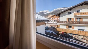 A view from a window overlooking a mountain village with wooden buildings and a snowy landscape.