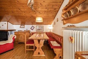 Un interior de madera con una mesa de comedor, bancos, un sofá rojo y un radiador.