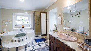 A bathroom with a bathtub, a sink, a large mirror, and a shower. - Pool suite with marble bath in exotic fruit orchard (Ribeira Grande)