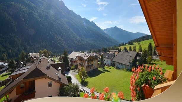 Un village de montagne aux bâtiments traditionnels, avec un ciel dégagé et une vue sur les montagnes environnantes.