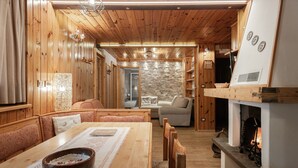 Un intérieur chaleureux en bois, avec un coin repas, des sièges et une cheminée.
