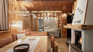 A cozy wooden interior with a dining area, seating, and a fireplace.