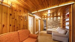 Un intérieur en bois avec un canapé, un fauteuil et un mur en pierre.