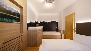A bedroom with a bed, a dresser, a vanity, a painting, and a door. - Charming Apartment “Majon d’Aisciuda Latemar” with Mountain View (Vigo di Fassa)