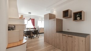 A modern kitchen with wooden cabinets, a dining area with chairs, and a built-in bench. - Charming Apartment “Majon d’Aisciuda Latemar” with Mountain View (Vigo di Fassa)